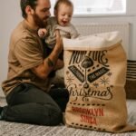 a man sitting on the floor holding a baby next to a bag